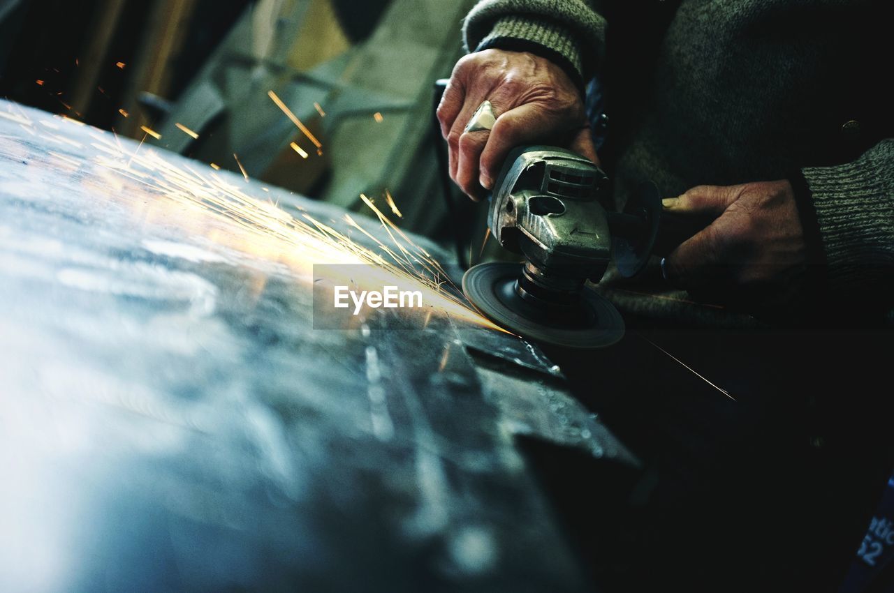 Midsection of man using circular saw at industry