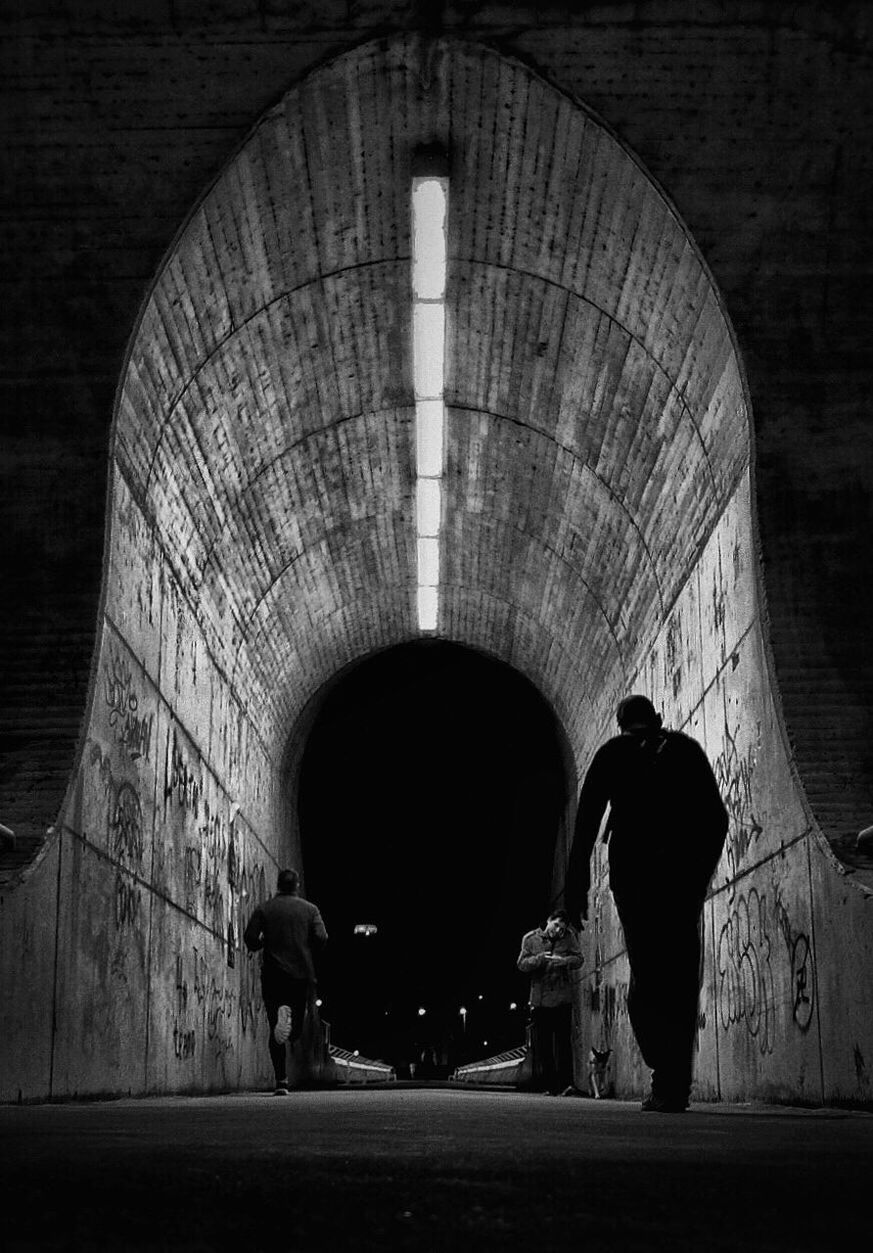 People walking in tunnel at night