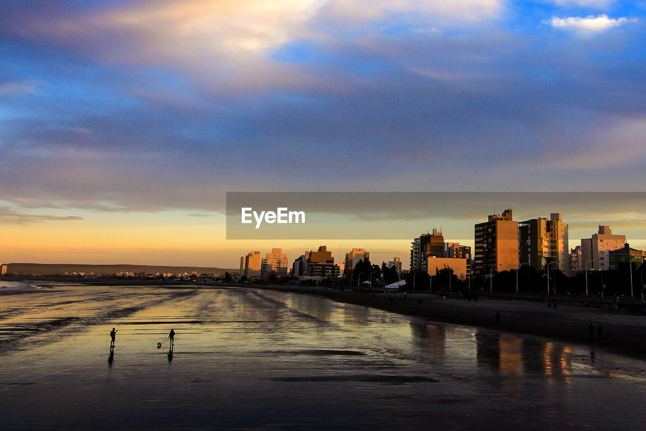 Scenic view of river and buildings against sky during sunset