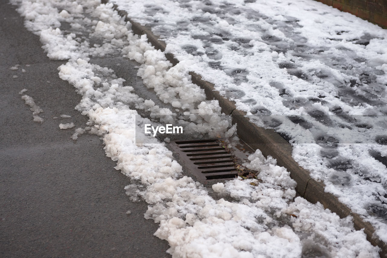 Urban scene of footsteps in a pavement full of snow. drain emerges from the accumulation of snow