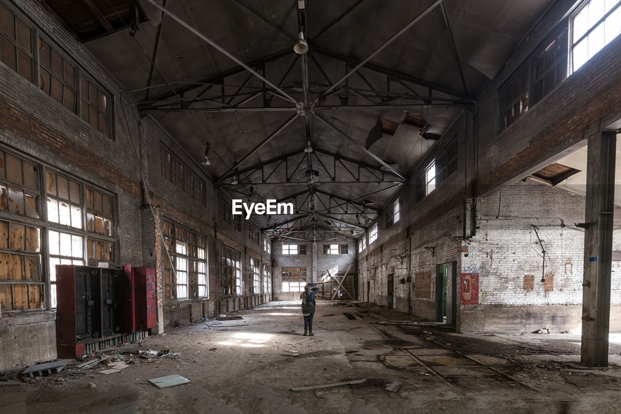 Rear view of woman standing in abandoned building