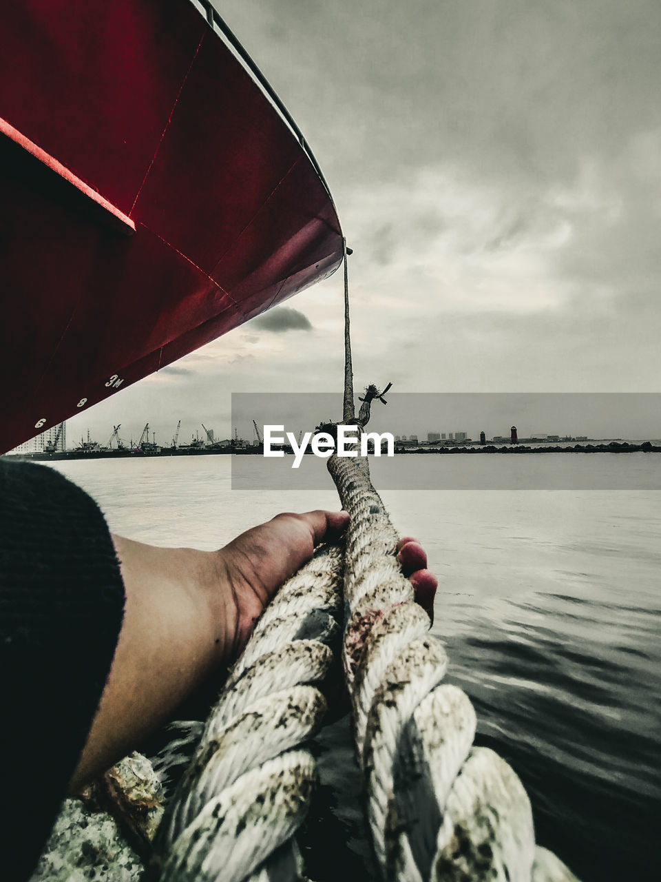 PERSON HOLDING ROPE AGAINST SEA