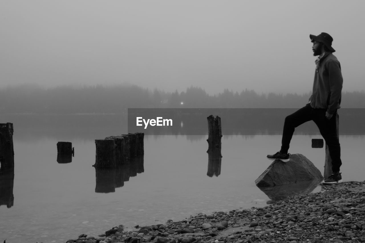 Full length of man standing by lakeshore against sky