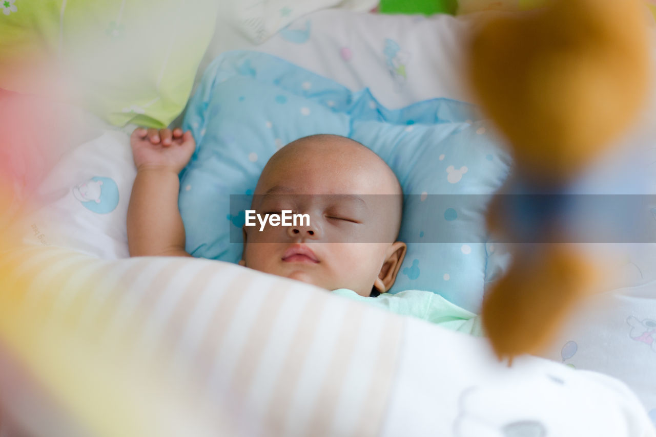 High angle view of baby boy sleeping on bed at home