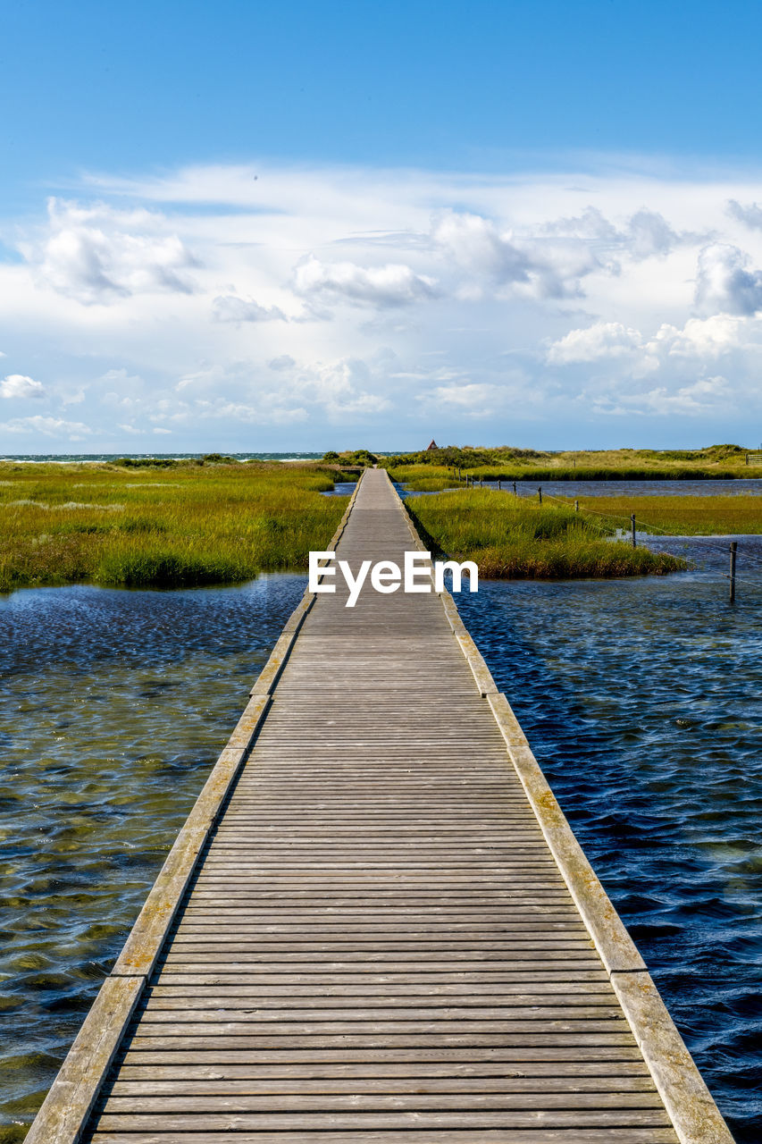 sky, water, horizon, the way forward, cloud, shore, nature, diminishing perspective, sea, scenics - nature, wood, beauty in nature, reflection, landscape, environment, tranquility, pier, tranquil scene, boardwalk, vanishing point, jetty, no people, land, day, footpath, sunlight, walkway, outdoors, reservoir, transportation, non-urban scene, blue, travel, plant, travel destinations, coast, idyllic, horizon over land, beach, architecture, urban skyline, summer, trip, holiday, grass, vacation, wetland
