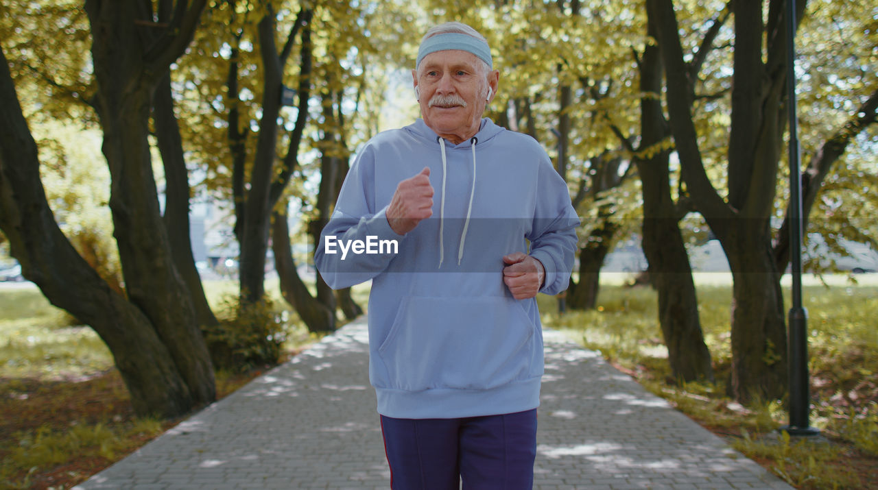 Senior man listening music while jogging in park