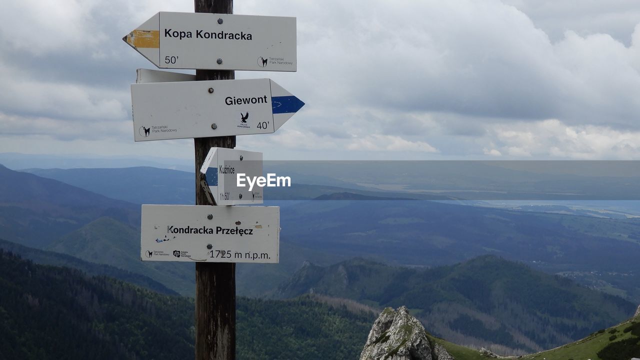 Information sign on mountain against sky