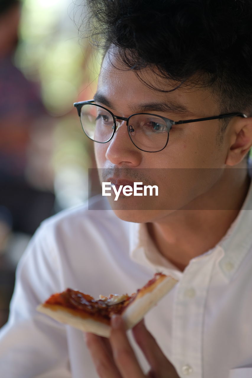 Close-up portrait of young man eating pizza