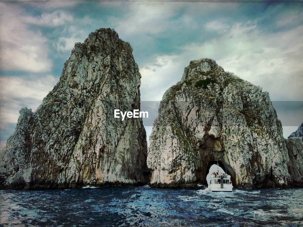 Rock formation on sea against cloudy sky