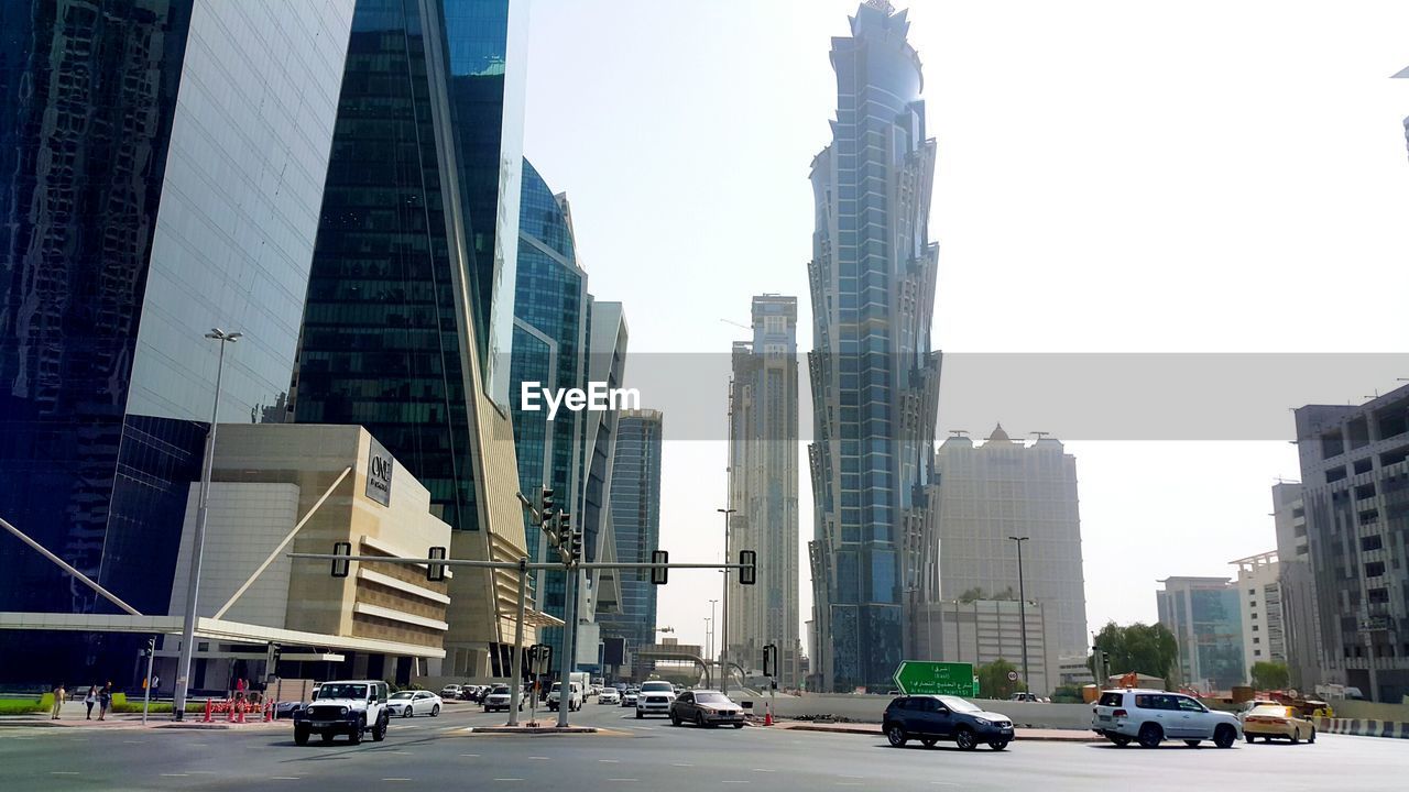 CARS ON ROAD AMIDST BUILDINGS IN CITY