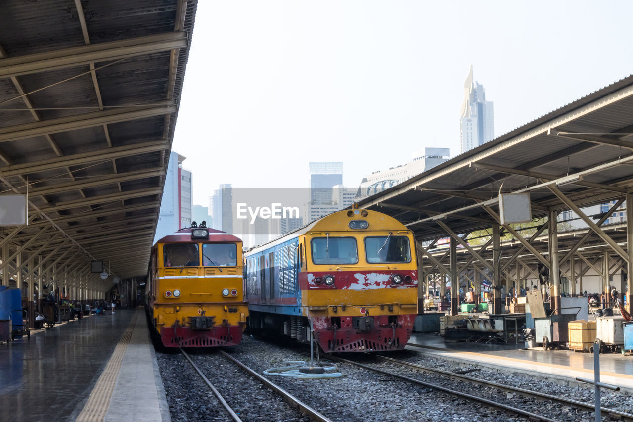 Train at railroad station in city against sky