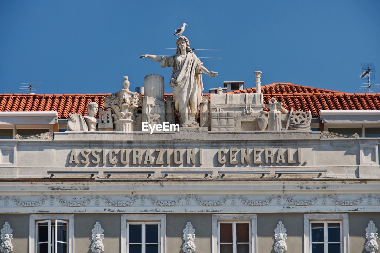 Low angle view of sculptures on historic building against clear sky