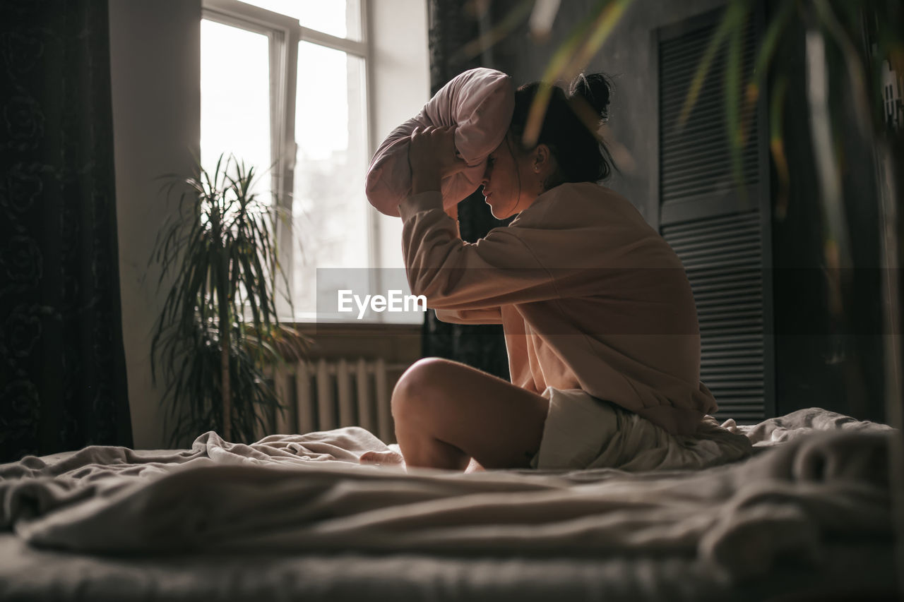 Woman sitting on bed at home