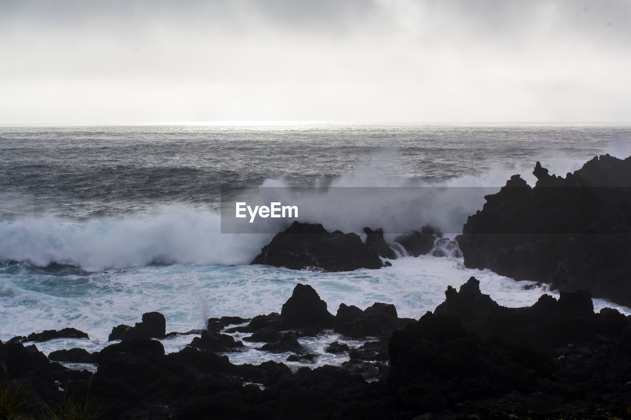 Waves crashing against black volcanic rock formations