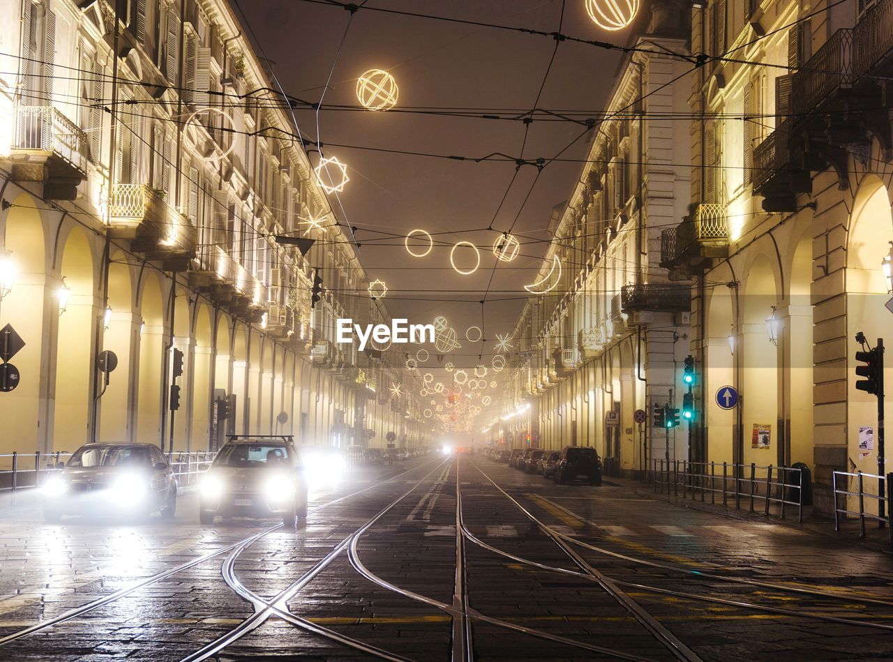 Illuminated street amidst buildings at night