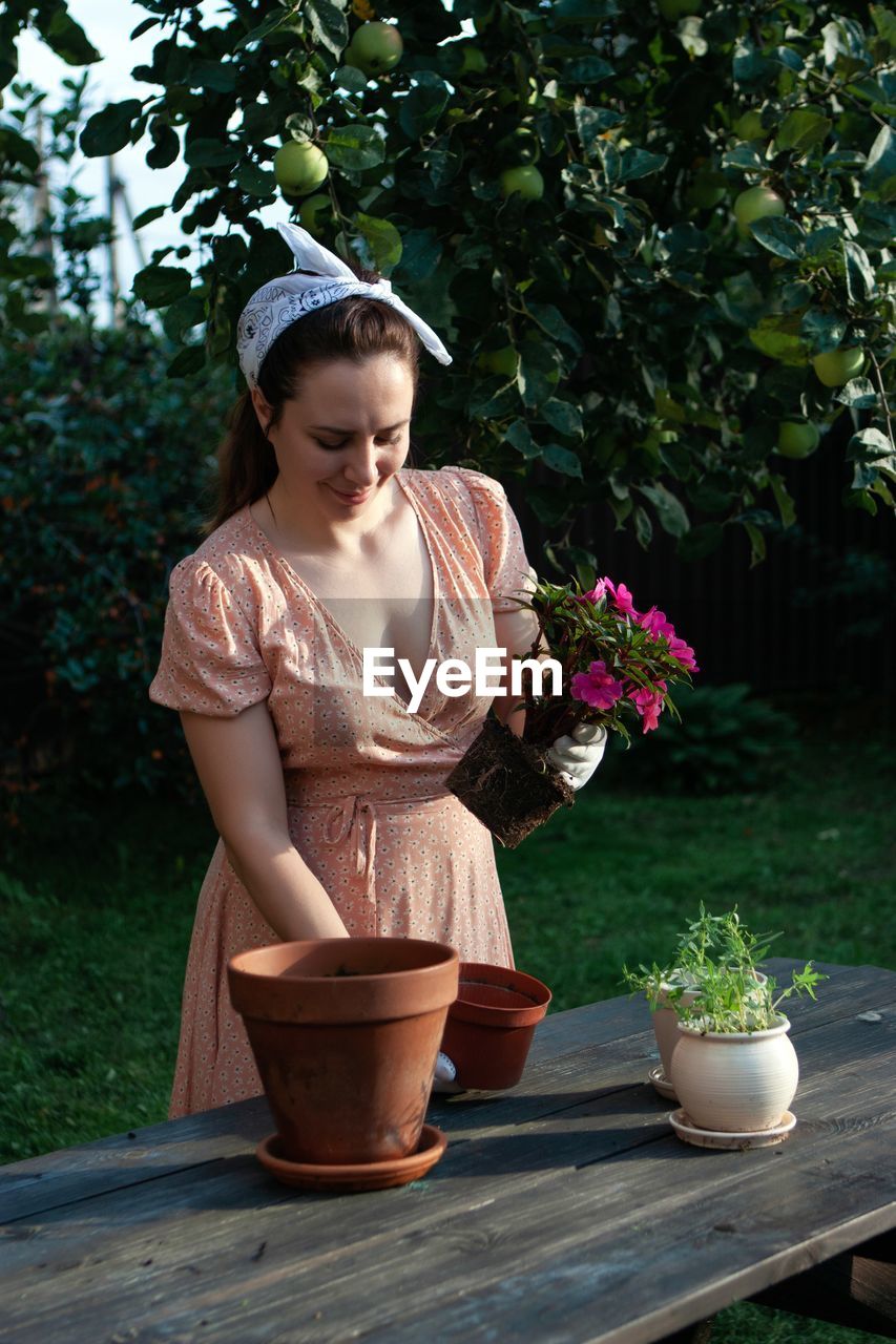 A woman replants an impatiens in a new pot