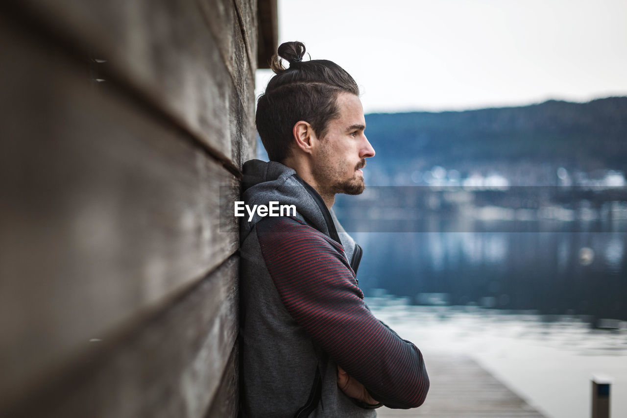 Side view of young man looking away while standing in water