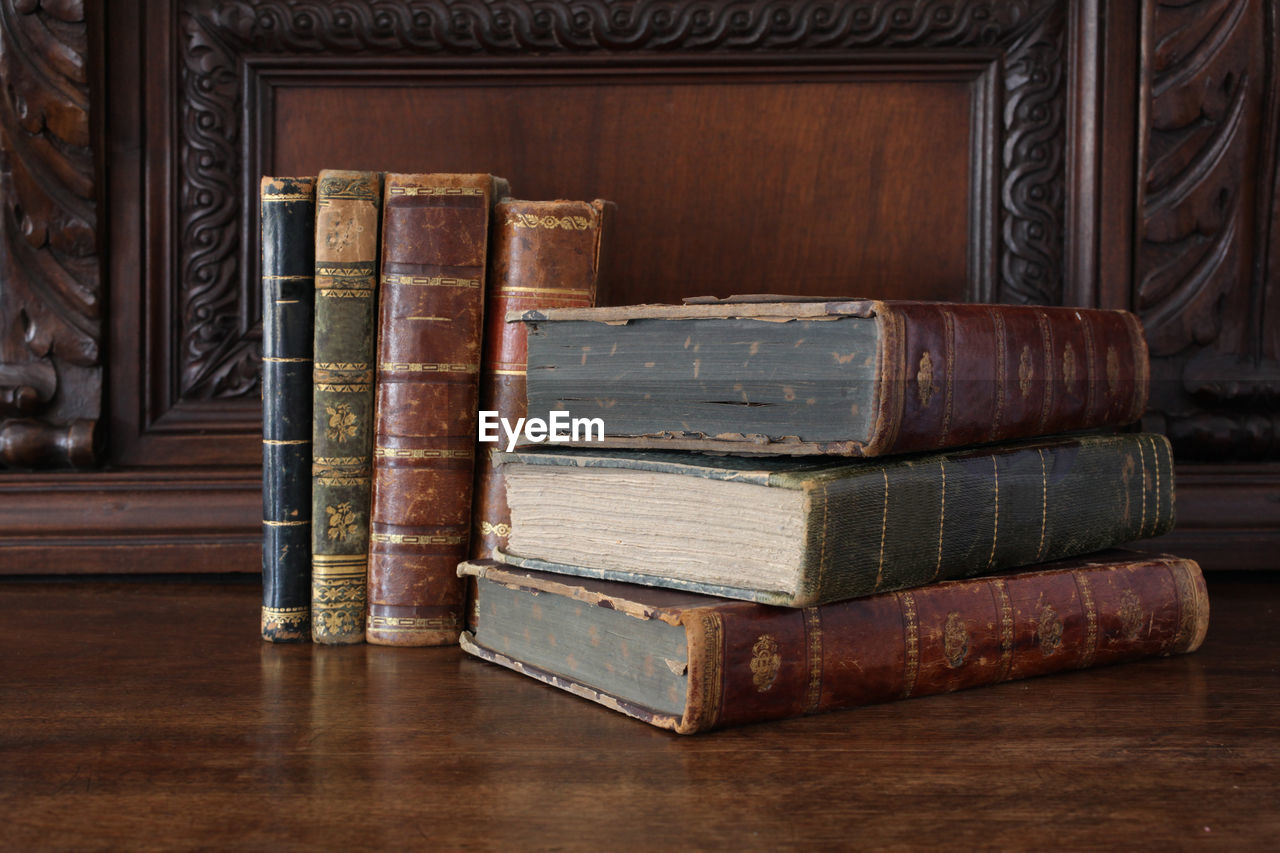 STACK OF OLD BOOKS ON TABLE IN SHELF