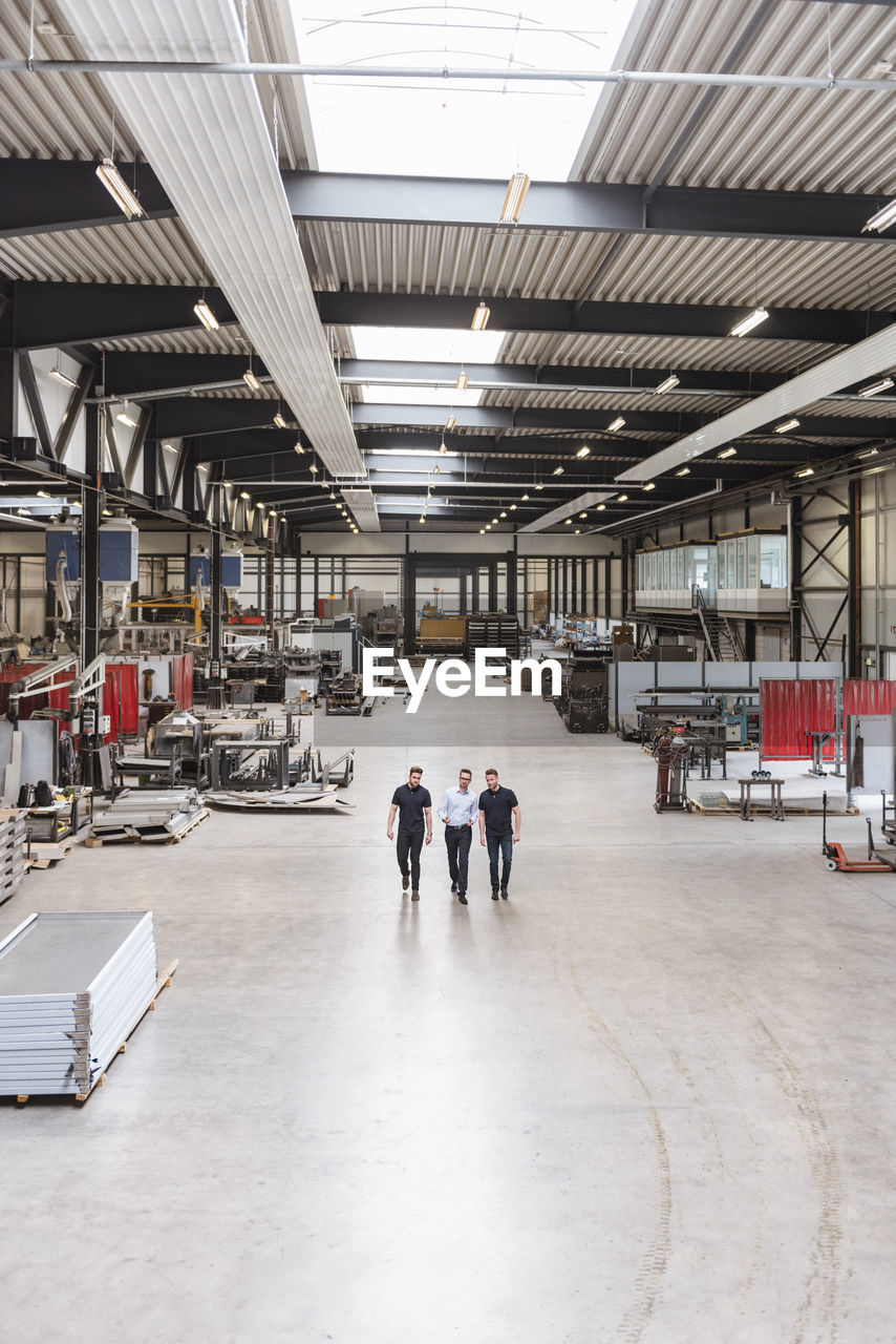 Three men walking and talking on factory shop floor