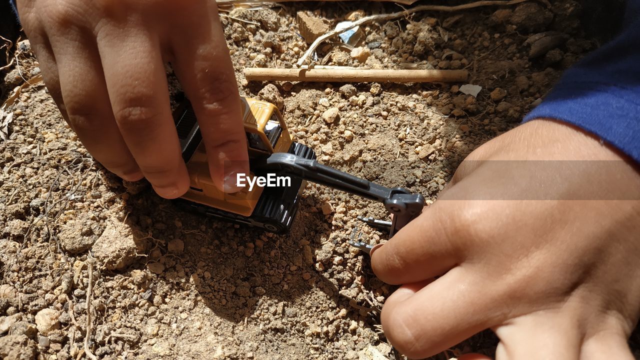 Cropped hands of child playing with toy on land