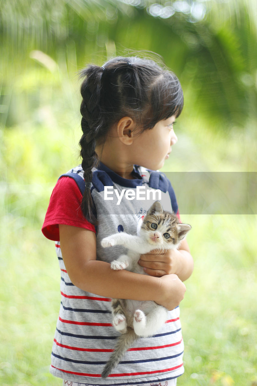 Cute girl holding cat outdoors