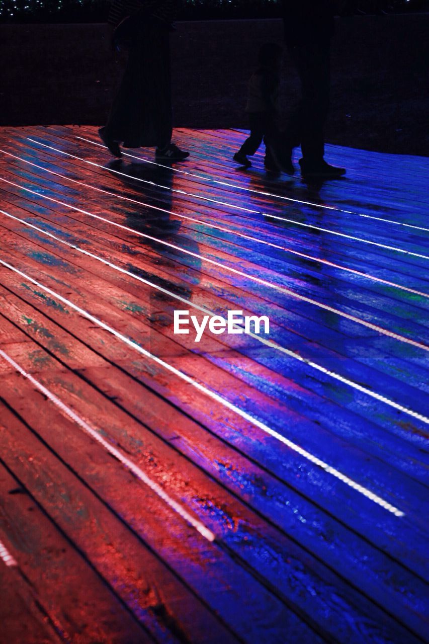 Low section of silhouette people walking on floor at night