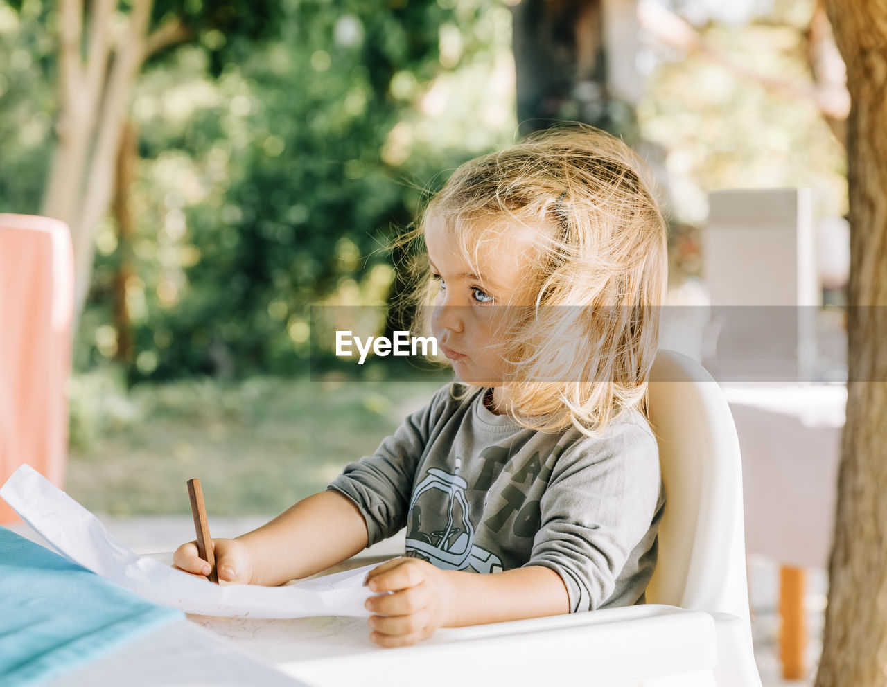 Girl looking away while drawing over paper on table