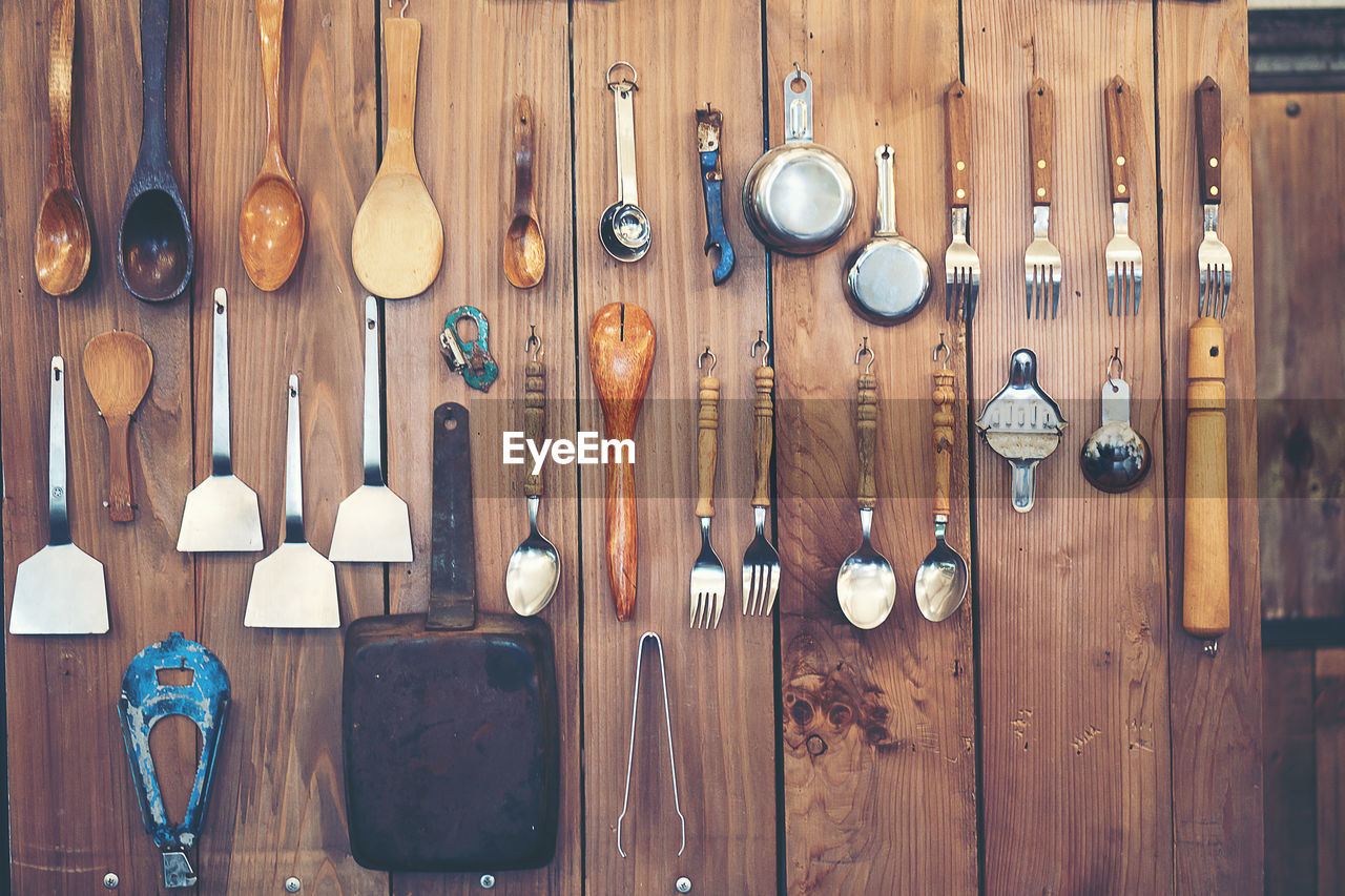 Full frame shot of wooden wall with eating utensils