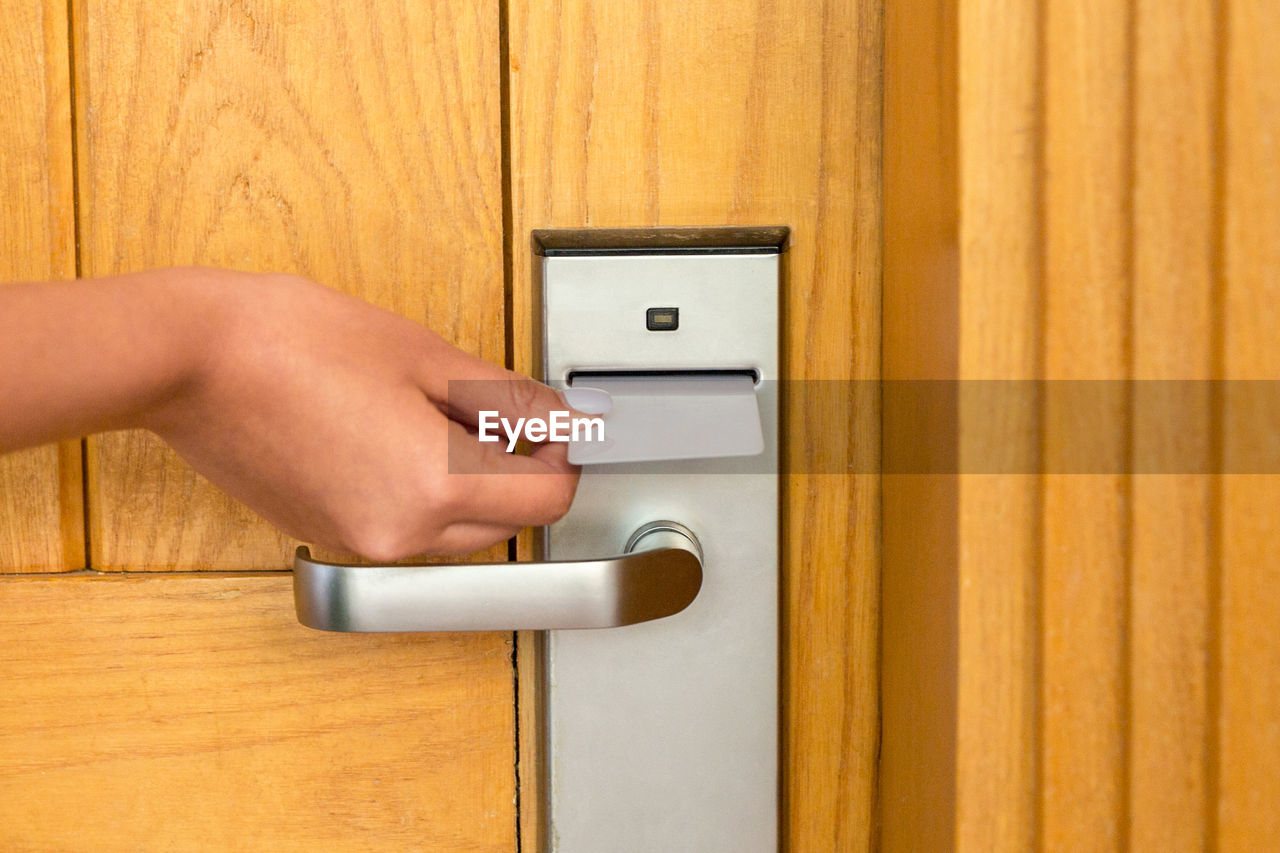 Cropped image of hand using access card to open door