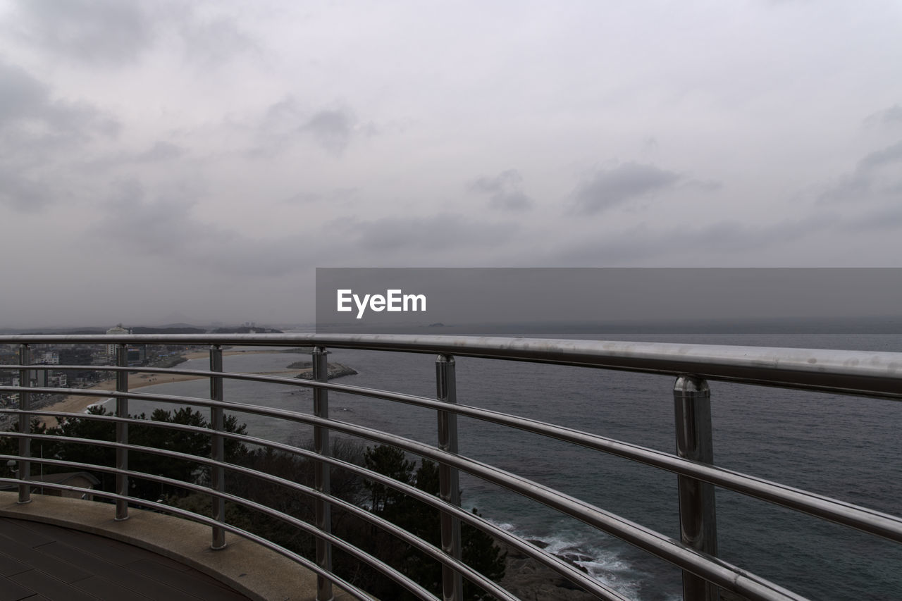 Scenic view of guard rail with sea against sky