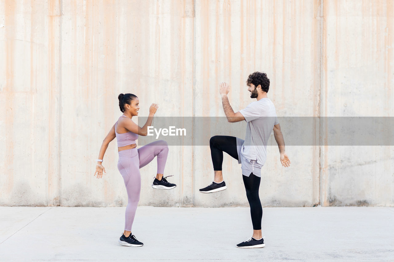 Side view of young determined diverse athletes in sportswear exercising and looking at each other