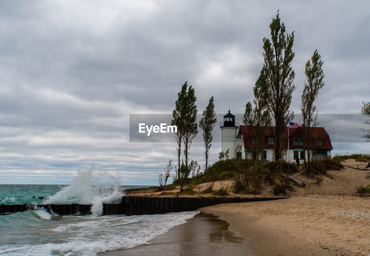 LIGHTHOUSE BY SEA AGAINST BUILDINGS