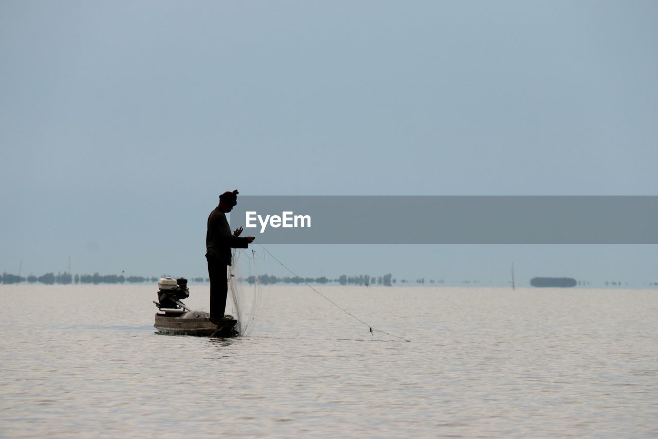 Man working in lake against clear sky