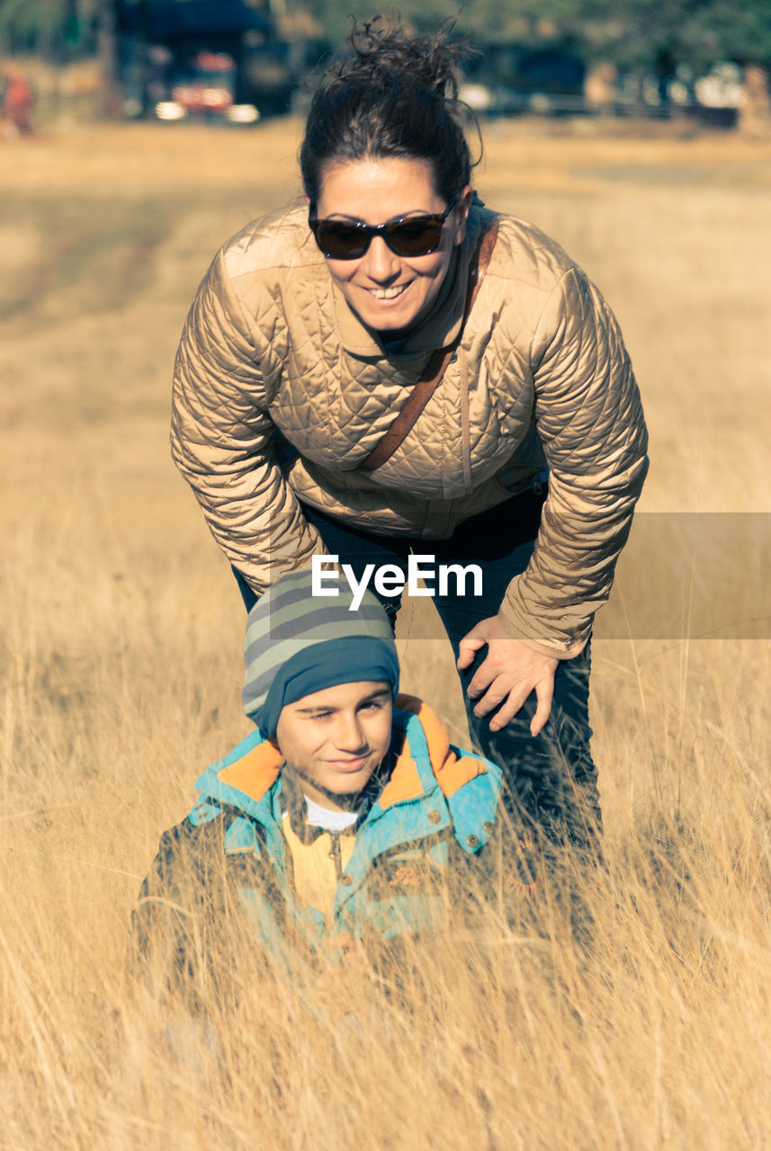 Portrait of mother and son smiling on grassy field