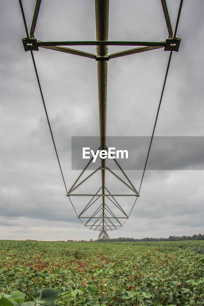 Low angle view of wind turbines on field against sky