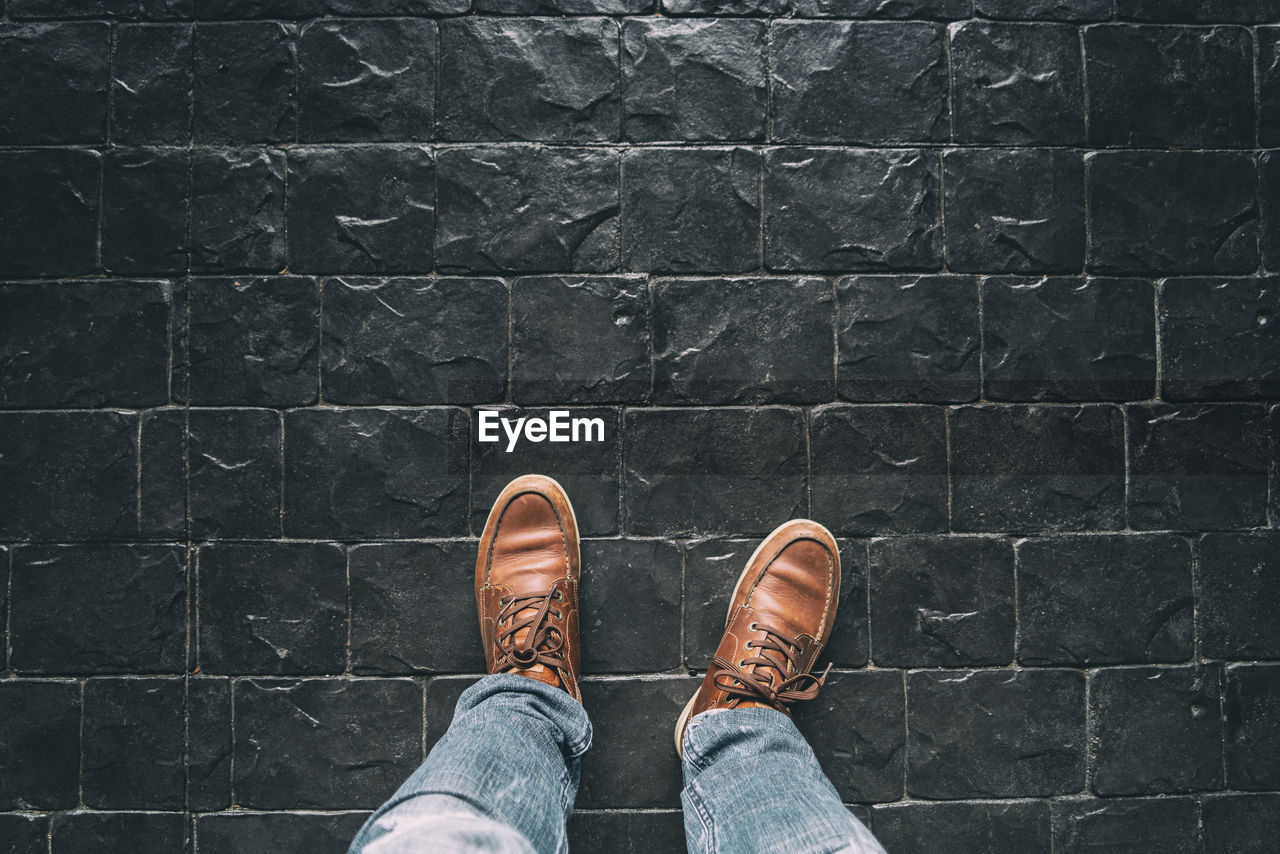 Low section of man standing on cobblestone