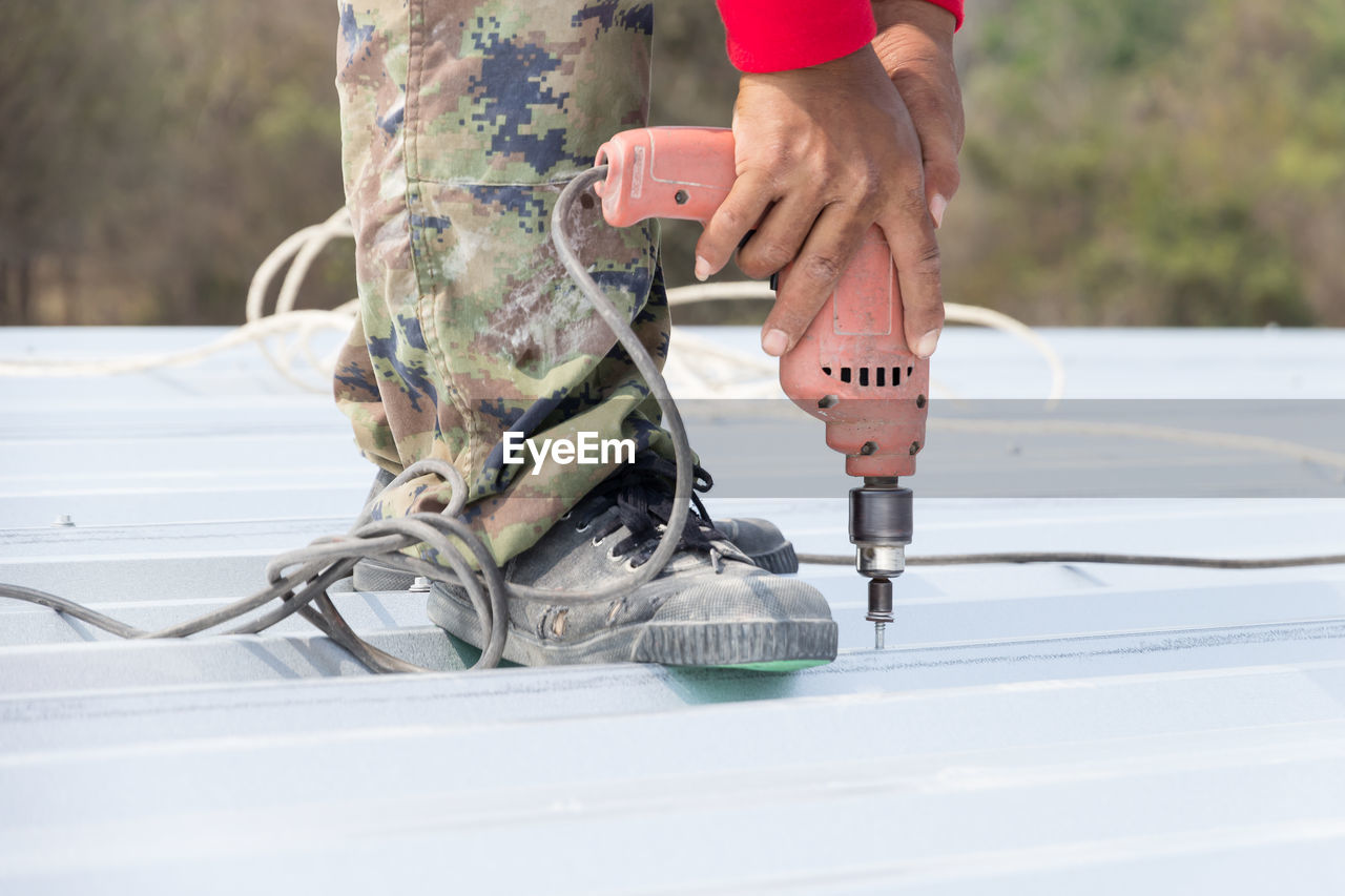 Low section of man drilling in metal