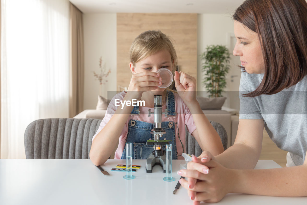 Mother helping daughter in science project at home