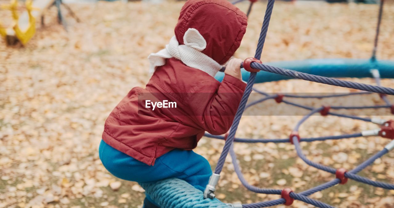 Low angle view of girl playing on rope in playground