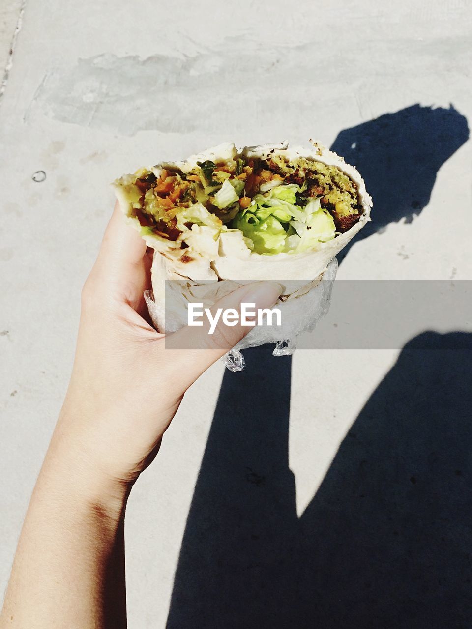 Cropped image of woman holding falafel burritos