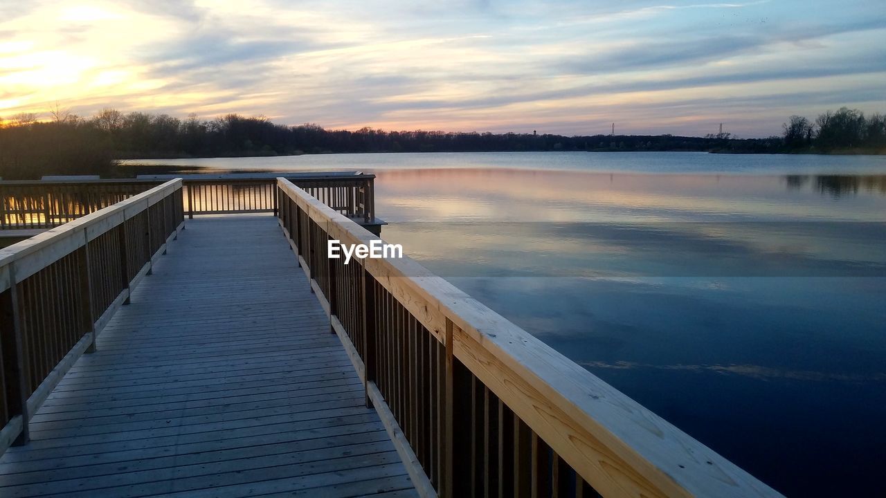 PIER OVER LAKE AGAINST SKY DURING SUNSET