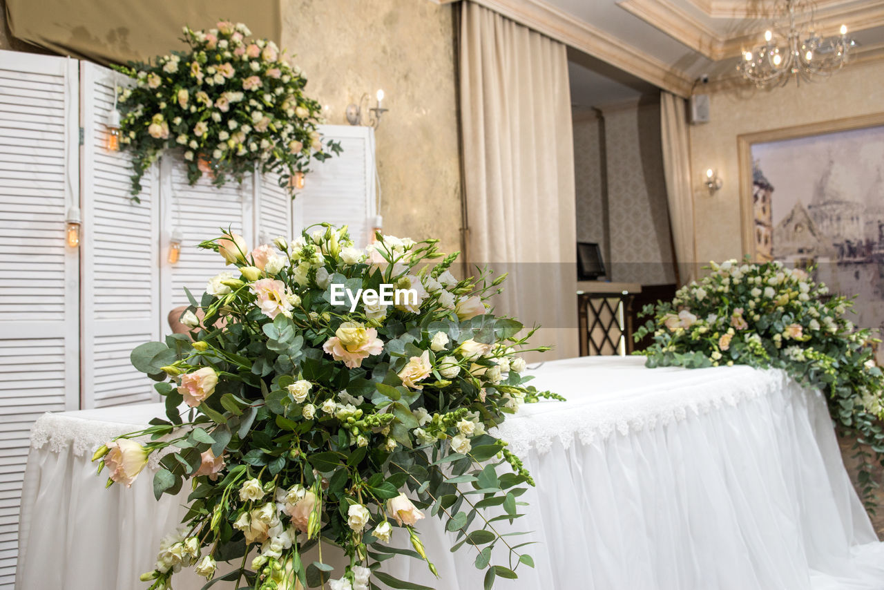 FLOWERING PLANTS AGAINST WHITE WALL AND POTTED PLANT