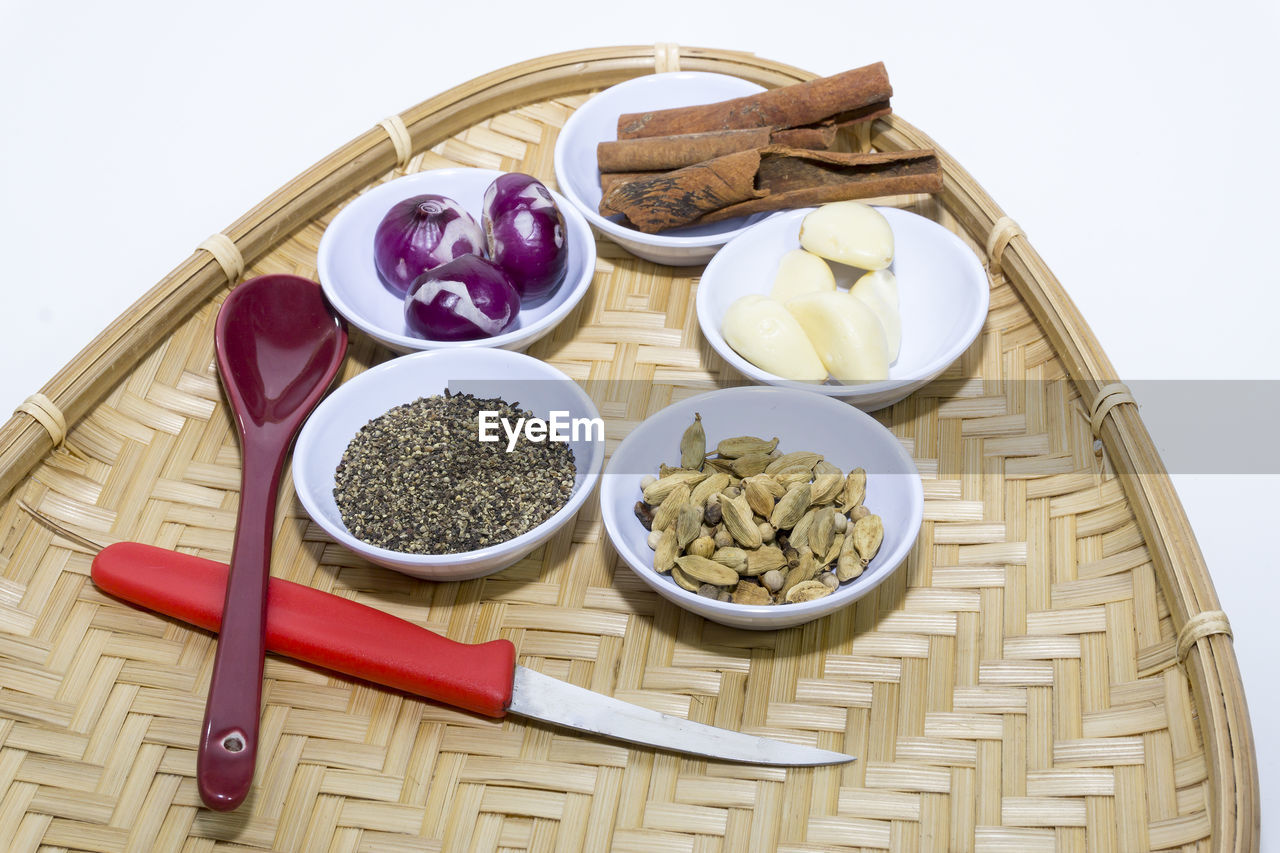 High angle view of spices and vegetables on wicker basket on white background