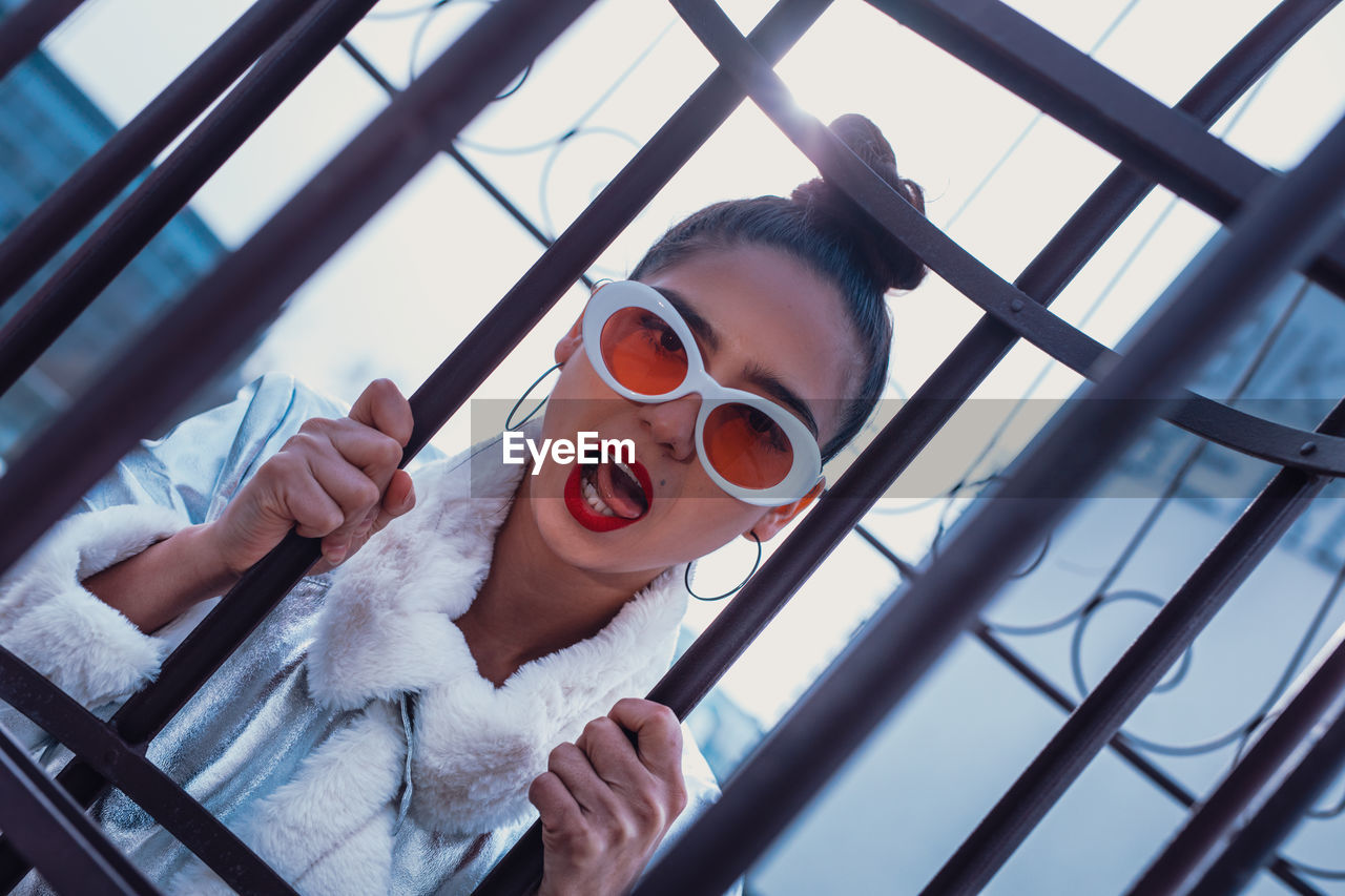 Portrait of woman in sunglasses against gate