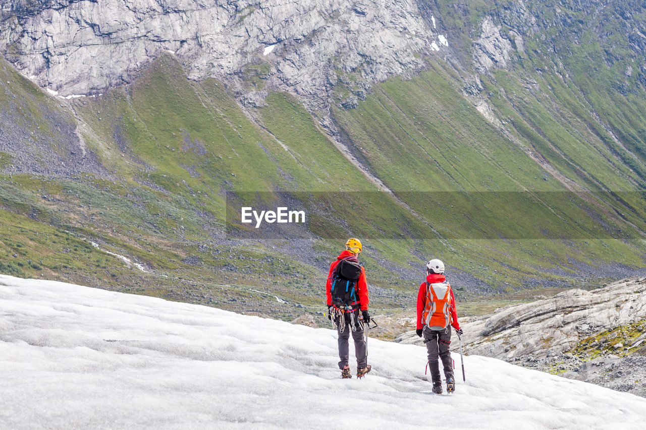 Rear view of people hiking on mountain during winter