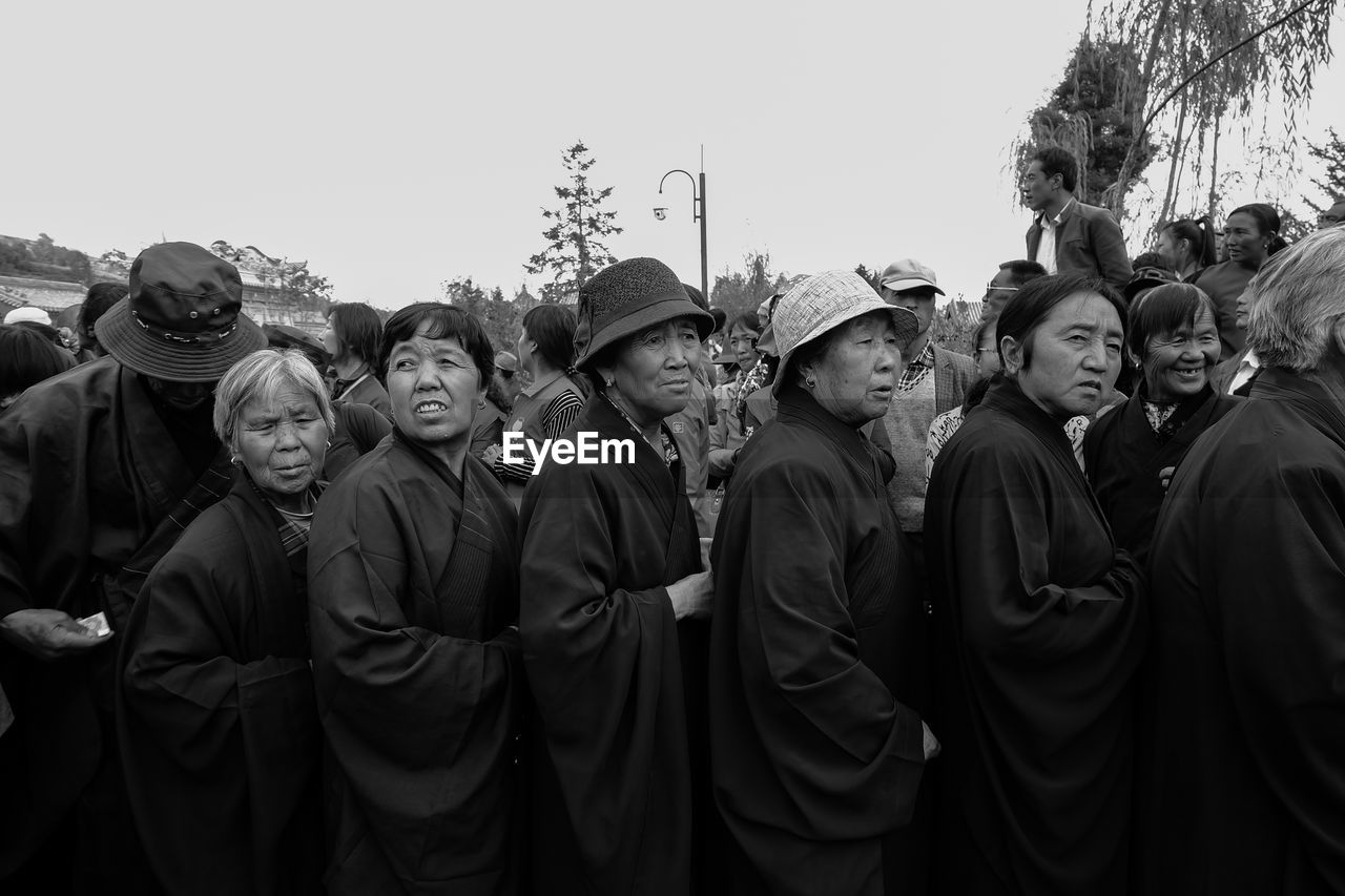 PANORAMIC SHOT OF PEOPLE STANDING IN FRONT OF TREES