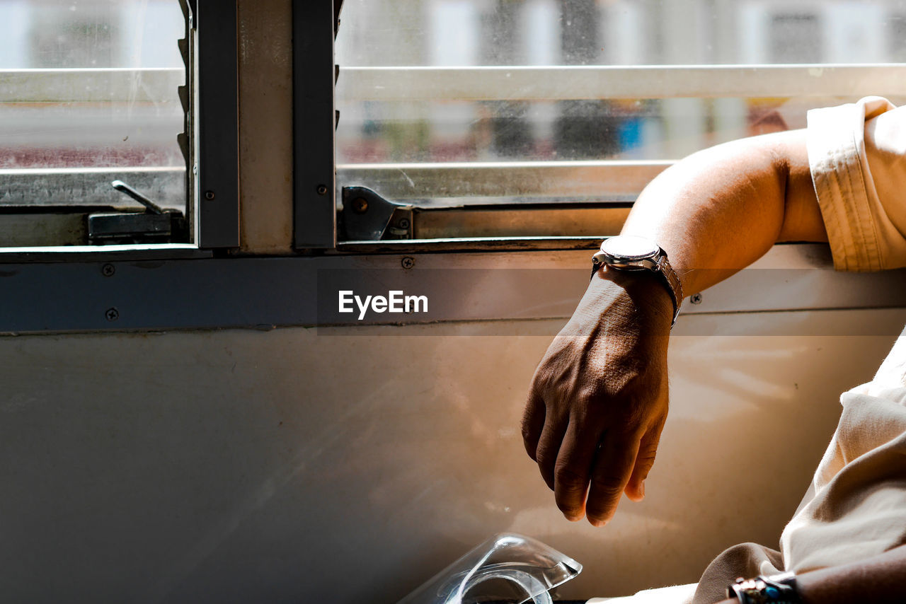 Close-up of man hand by window in train