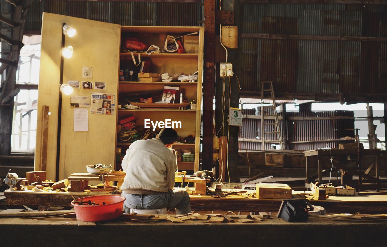 REAR VIEW OF MAN WORKING AT MARKET