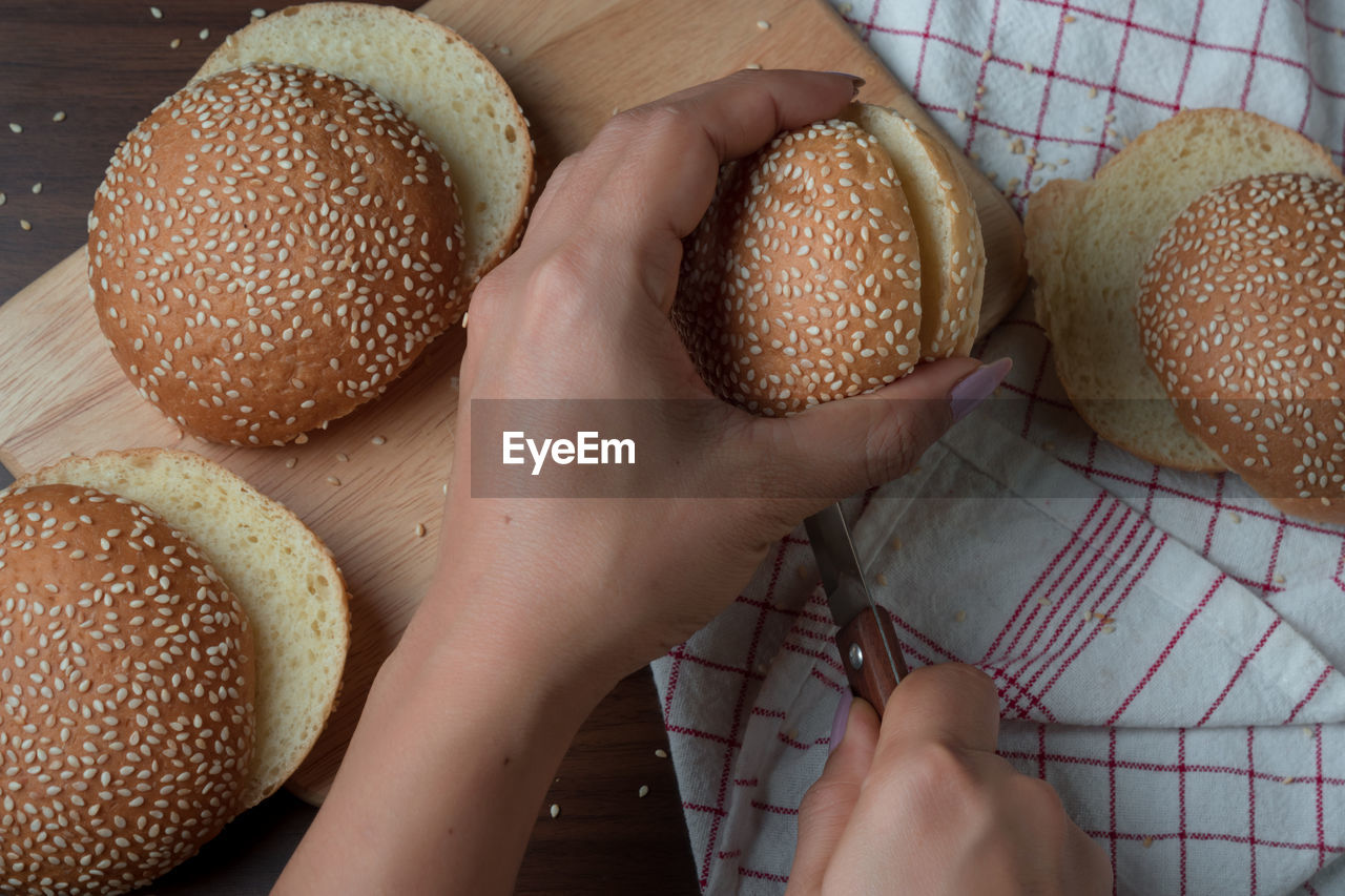 Cropped hands cutting bun at table