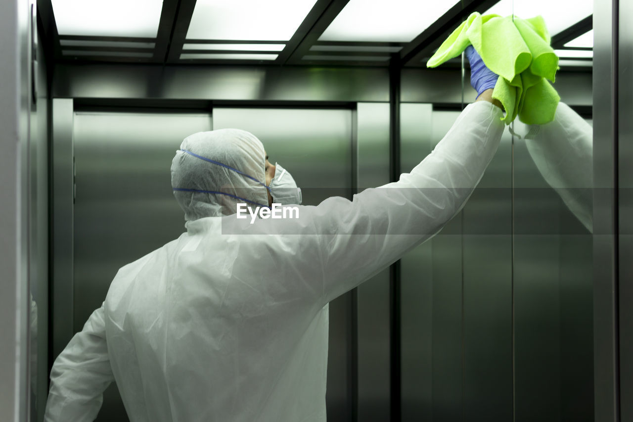 Coronavirus. worker disinfecting hospital elevator to avoid contagion.